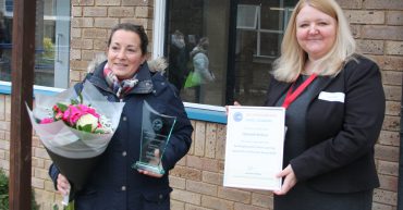 Two women at award presentation with flowers and certificate