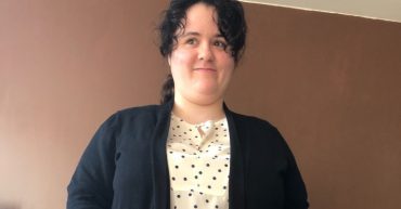 Woman in white spotty top and black cardigan