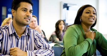 A man and a woman sitting at a desk in a classroom