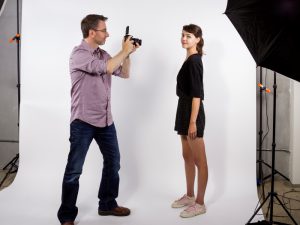 Man taking photograph of girl in studio with umbrella