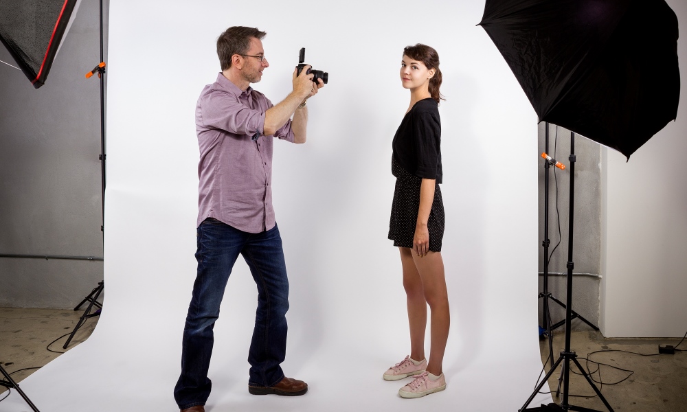 Man taking photograph of girl in studio with umbrella