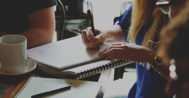 Woman writing on notepad in cafe