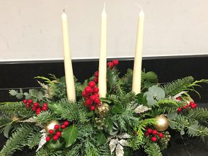 Christmas floral arrangement with candles and berries