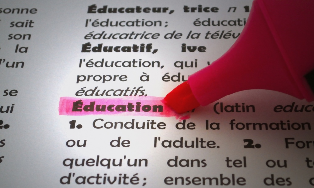 Page of french dictionary with pink highlighter on word Education