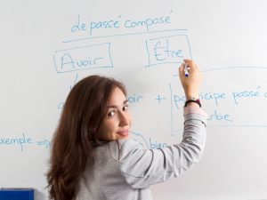 Woman writing on French verbs on whiteboard