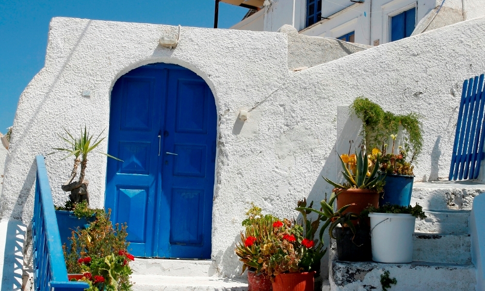 Blue door in white house with flowerpots in front