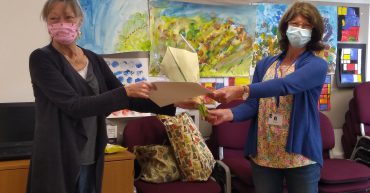 woman being presented with certificate and flowers