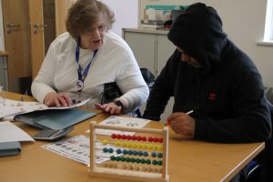 man learning maths with learning support assistant
