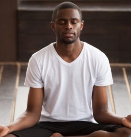 Man sitting in yoga pose with eyes closed