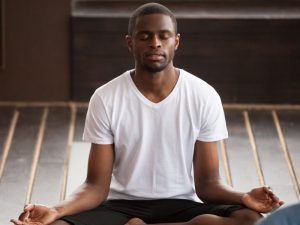 Man sitting in yoga pose with eyes closed