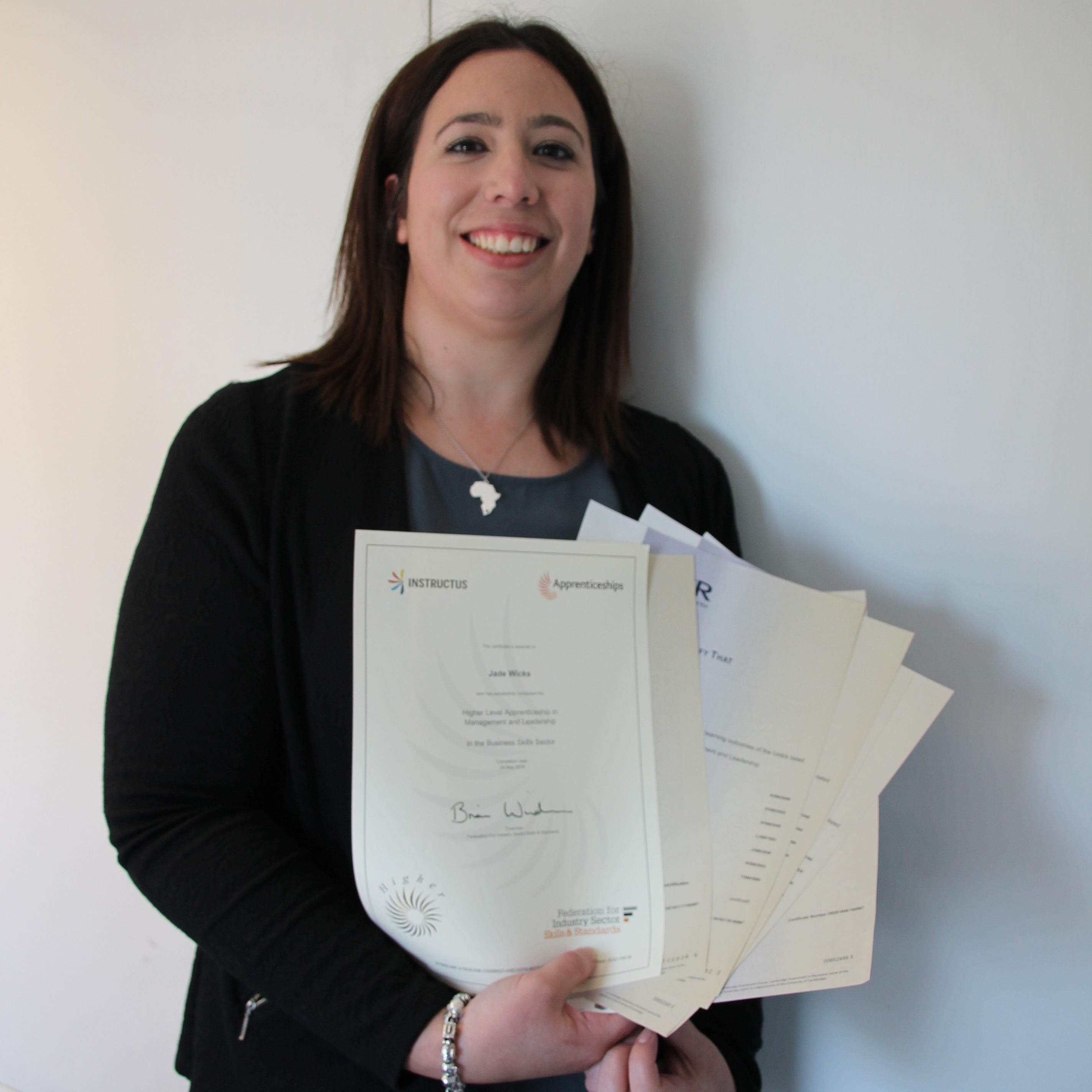Lady with long dark hair holding certificates