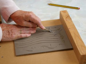 Hands cutting a lino print template