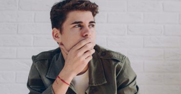 Young man thinking with hand over his face