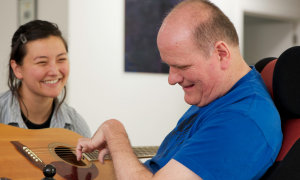 man playing guitar with woman smiling