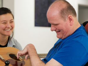 man playing guitar with woman smiling