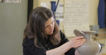 Woman in black jumper working on clay vase