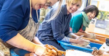 Three women making pots on a pottery wheel
