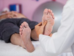 person practising reflexology on a man's feet