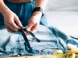 Person altering the zip on a pair of jeans