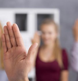 Hand using sign language with three people in background