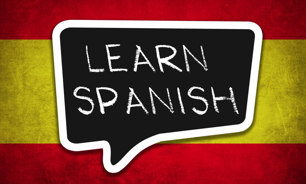 Learn spanish text in speech bubble in front of Spanish flag