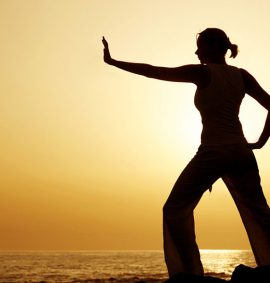 woman practising tai chi with a sunset