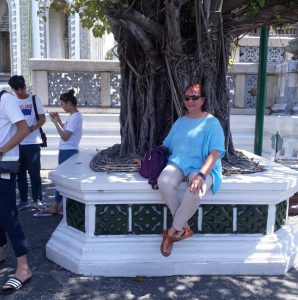 Lady in blue top wearing sunglasses underneath a tree