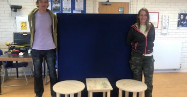 A man and a woman with three wooden tables that they made