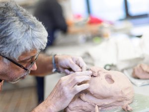 man sculpting a face in clay