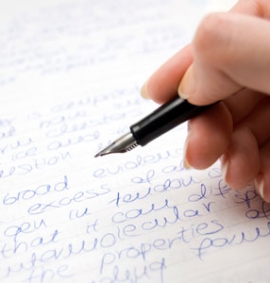 A fountain pen in someones hand writing in a book