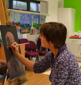 Adult Learner Student painting on a canvas in a Art class
